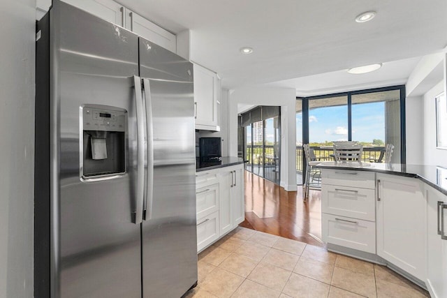 kitchen with light tile patterned flooring, floor to ceiling windows, white cabinets, and stainless steel refrigerator with ice dispenser