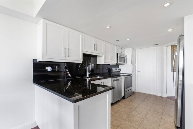 kitchen featuring white cabinetry, sink, backsplash, kitchen peninsula, and stainless steel appliances