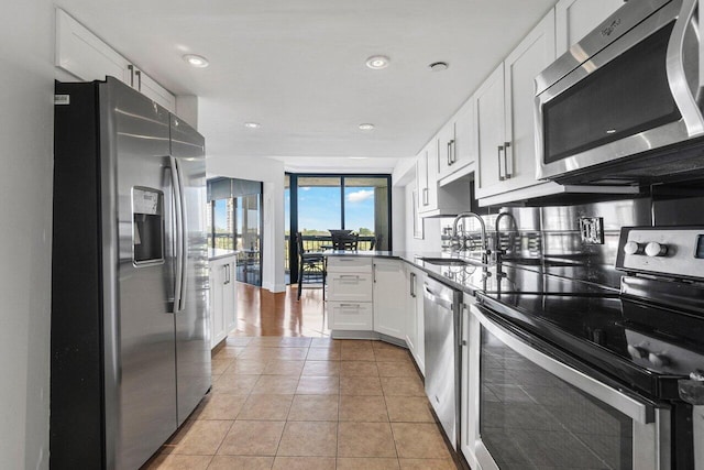 kitchen with sink, white cabinetry, light tile patterned floors, appliances with stainless steel finishes, and kitchen peninsula