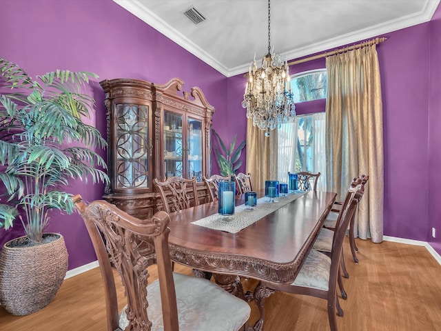 dining room featuring crown molding, wood-type flooring, and a chandelier