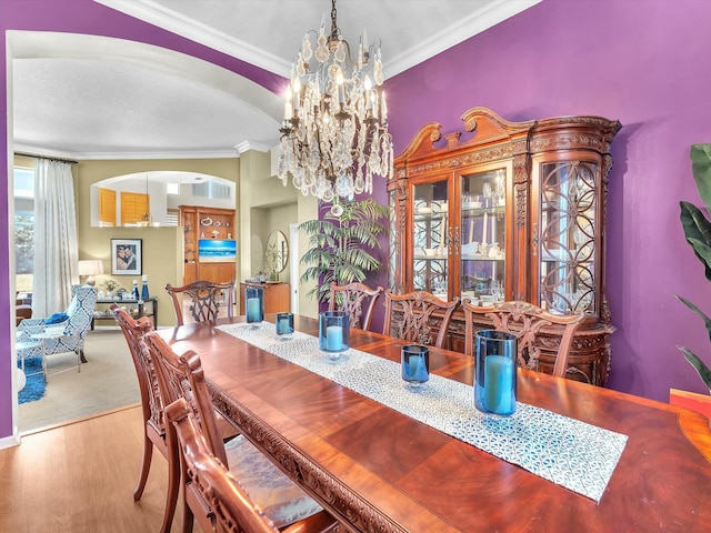 dining space with an inviting chandelier, crown molding, and light hardwood / wood-style flooring