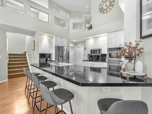 kitchen with appliances with stainless steel finishes, sink, a breakfast bar area, white cabinets, and kitchen peninsula