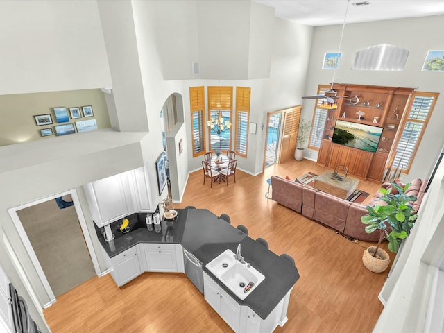 living room featuring a notable chandelier, a towering ceiling, and light wood-type flooring