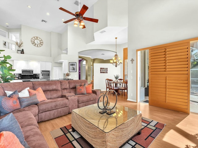 living room featuring ceiling fan with notable chandelier and light hardwood / wood-style flooring