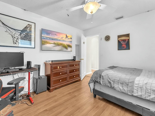 bedroom with ceiling fan, light hardwood / wood-style flooring, and a textured ceiling