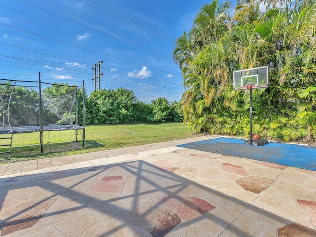 view of sport court with a trampoline and a lawn