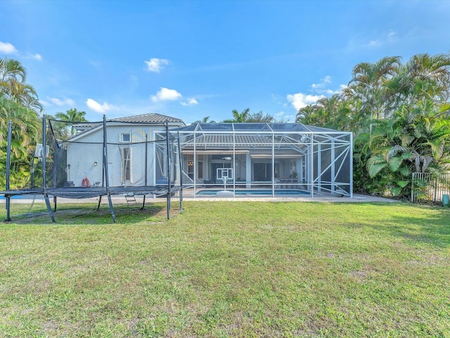 rear view of house featuring glass enclosure and a lawn