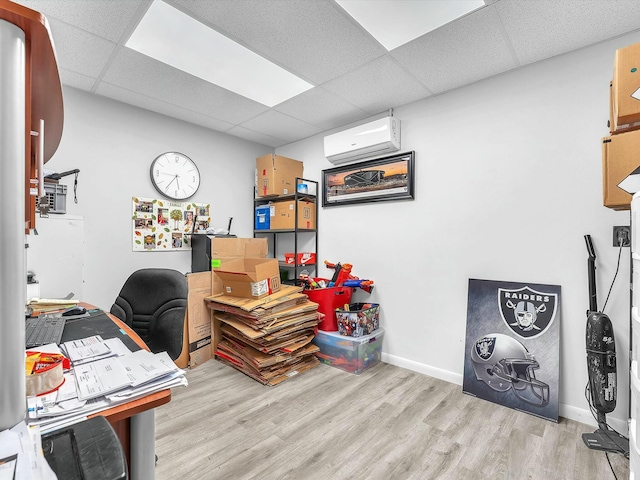 office featuring a paneled ceiling, a wall mounted air conditioner, and light hardwood / wood-style floors