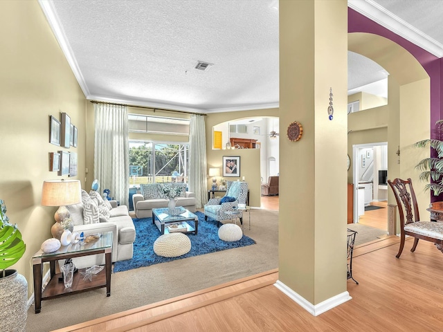 living room with ornamental molding, a textured ceiling, and light wood-type flooring