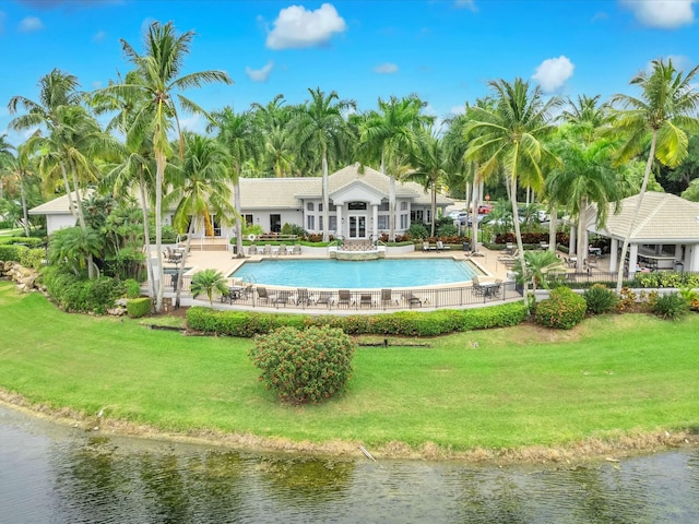 view of pool with a water view, a patio area, and a lawn