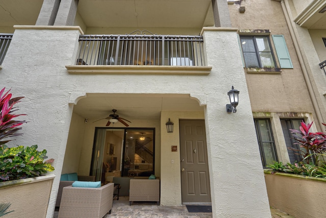 view of exterior entry with a balcony, an outdoor hangout area, and ceiling fan