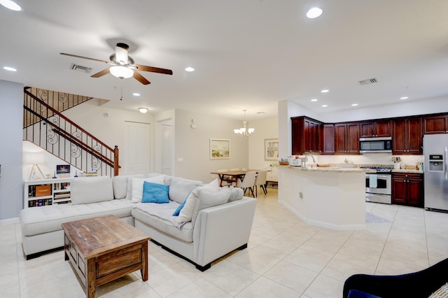 tiled living room featuring sink and ceiling fan with notable chandelier