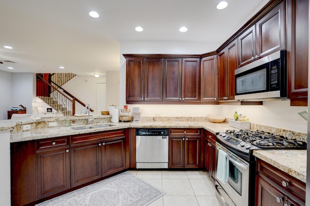 kitchen with sink, light tile patterned floors, light stone counters, kitchen peninsula, and stainless steel appliances