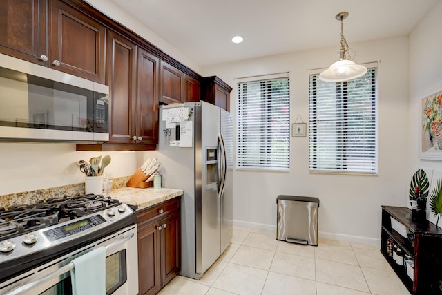 kitchen featuring hanging light fixtures, light stone countertops, a healthy amount of sunlight, and appliances with stainless steel finishes