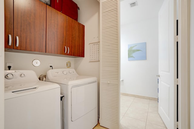 laundry room with light tile patterned floors, washer and clothes dryer, and cabinets