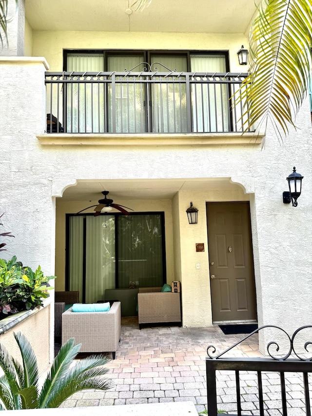 doorway to property with ceiling fan, a patio, a balcony, an outdoor hangout area, and stucco siding