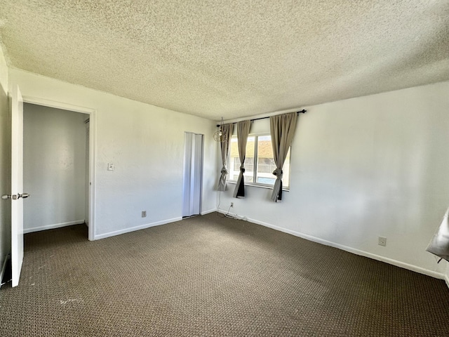 unfurnished bedroom with a textured ceiling, dark carpet, and a closet