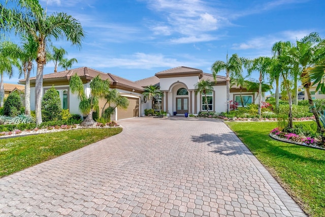 mediterranean / spanish home featuring a garage and a front lawn