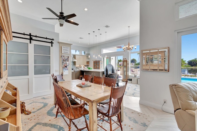 dining area with crown molding, a barn door, plenty of natural light, and ceiling fan with notable chandelier