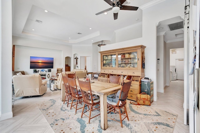 dining space featuring a tray ceiling, ceiling fan, crown molding, and light parquet flooring