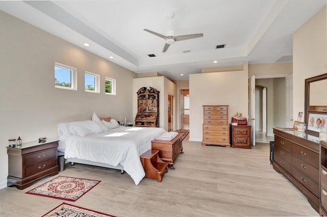 bedroom with a raised ceiling, ceiling fan, and light hardwood / wood-style flooring