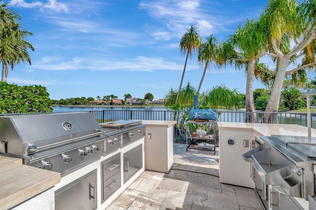 view of patio / terrace with a water view, an outdoor kitchen, and grilling area