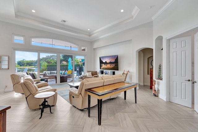 living room featuring a tray ceiling, a towering ceiling, ornamental molding, and light parquet flooring