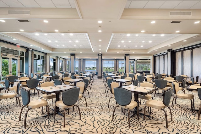 dining room featuring a raised ceiling, a healthy amount of sunlight, and light colored carpet