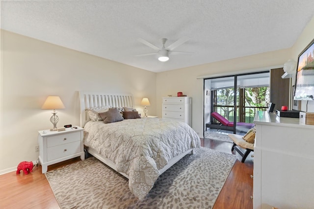 bedroom with ceiling fan, hardwood / wood-style floors, access to exterior, and a textured ceiling