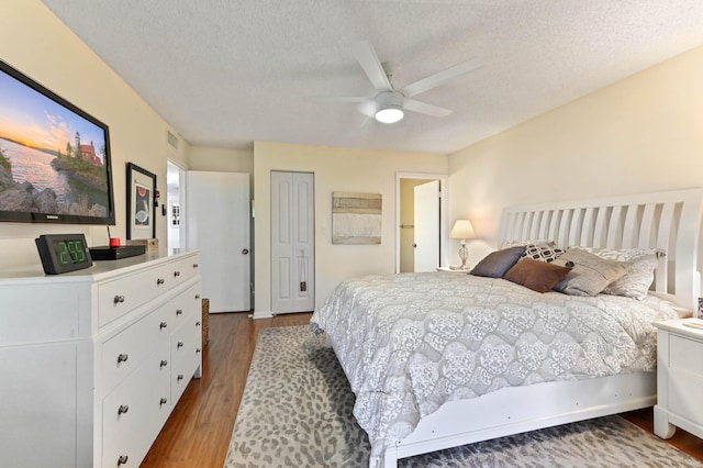 bedroom featuring hardwood / wood-style flooring, ceiling fan, and a textured ceiling