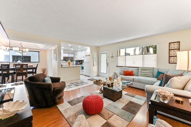 living room featuring an inviting chandelier, light hardwood / wood-style flooring, and a textured ceiling