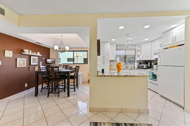 kitchen with white appliances, light stone countertops, white cabinets, light tile patterned flooring, and kitchen peninsula