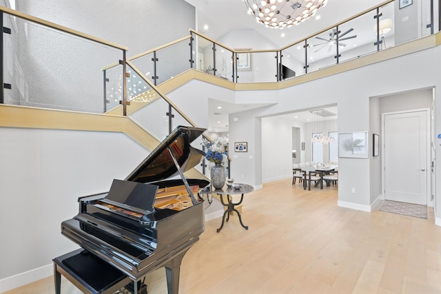 misc room with hardwood / wood-style flooring, a towering ceiling, and an inviting chandelier