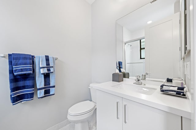 bathroom featuring vanity, toilet, and a shower with shower door