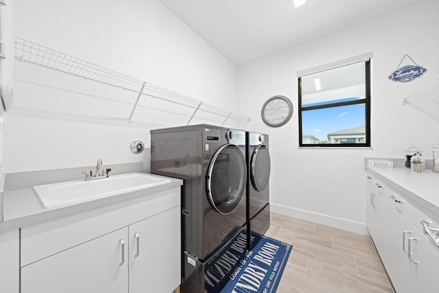 washroom with cabinets, sink, and washing machine and clothes dryer