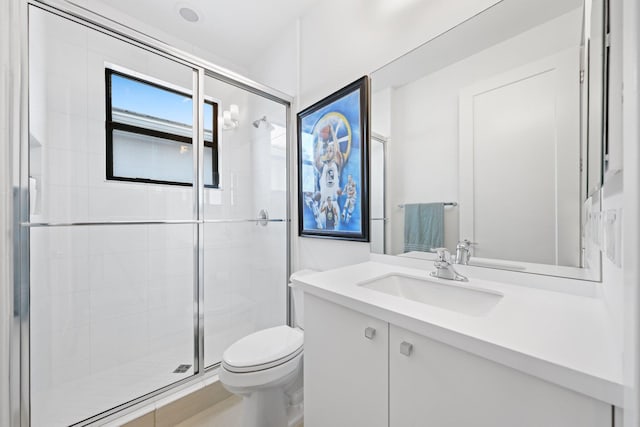 bathroom featuring vanity, a shower with shower door, and toilet