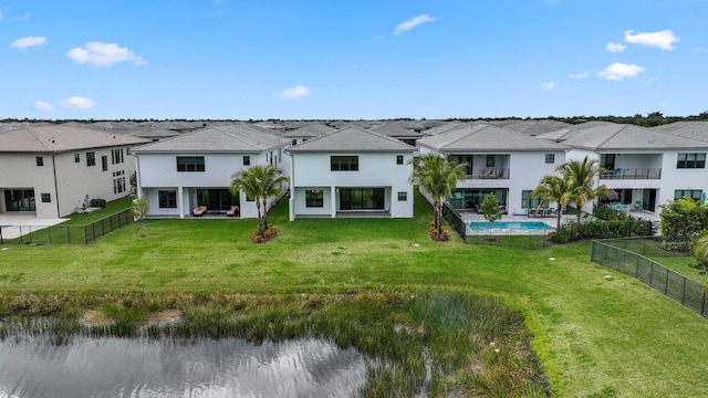 rear view of property with a fenced in pool and a lawn