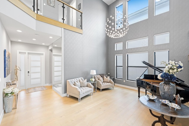 sitting room featuring a high ceiling, an inviting chandelier, and light hardwood / wood-style flooring