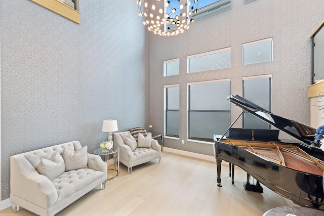 sitting room with hardwood / wood-style flooring, a chandelier, and a high ceiling