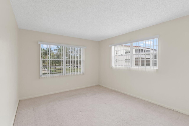 empty room with a textured ceiling, a healthy amount of sunlight, and carpet