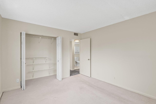 unfurnished bedroom featuring light colored carpet, a closet, and a textured ceiling