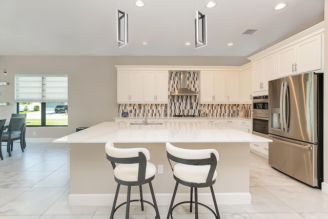 kitchen with appliances with stainless steel finishes, sink, a kitchen island with sink, and wall chimney range hood