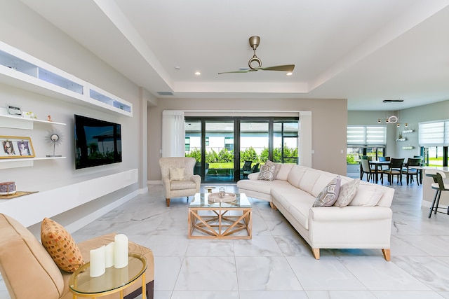 living room featuring a raised ceiling and ceiling fan