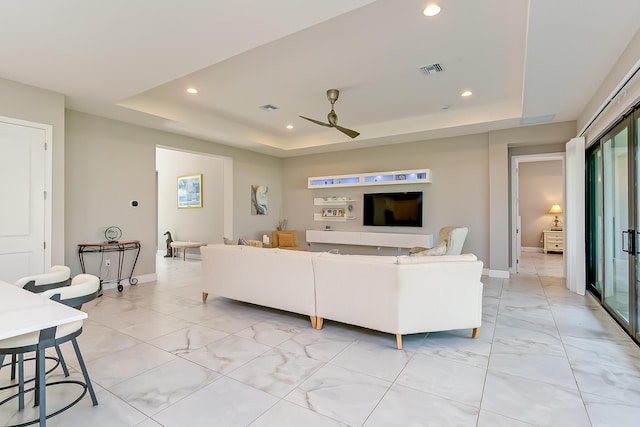 living room with ceiling fan and a tray ceiling