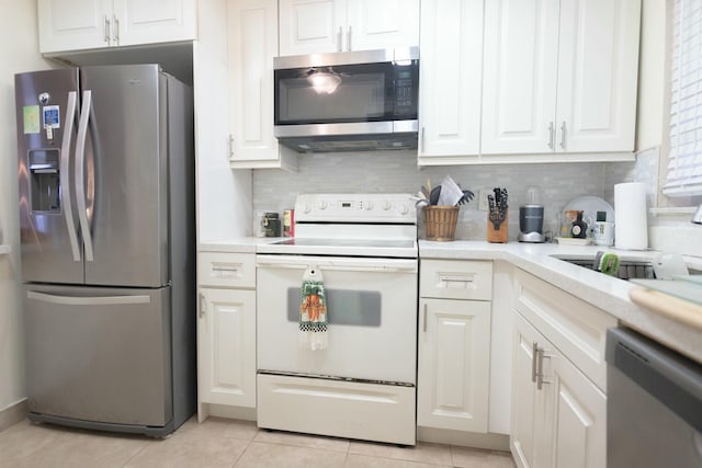 kitchen featuring light tile patterned flooring, appliances with stainless steel finishes, tasteful backsplash, and white cabinets