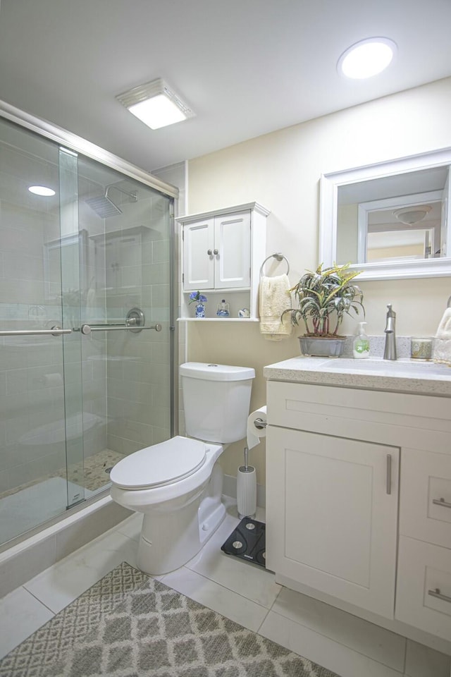 bathroom with toilet, vanity, tile patterned floors, and a shower with shower door