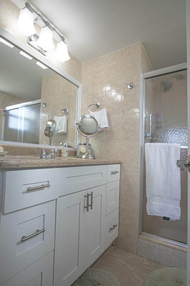 bathroom featuring vanity, tile walls, tile patterned floors, and a shower with shower door