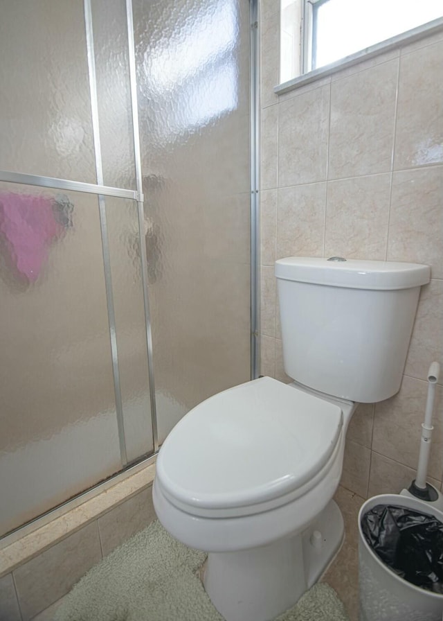 bathroom featuring tile walls, toilet, and walk in shower