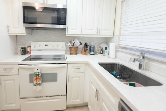 kitchen with sink, backsplash, white cabinets, and white range with electric stovetop