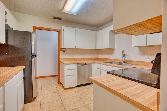 kitchen with visible vents, a sink, white cabinetry, appliances with stainless steel finishes, and light tile patterned floors